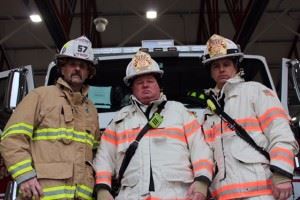 3 firefighters in front of fire engine